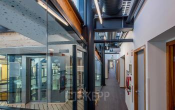 Kantoorpand aan Fokkerstraat 16 in Leusden met moderne glazen en houten interieurdetails. Geschikt voor kantoorruimte huren met verluchte gangen en zicht op meerdere kantoren.