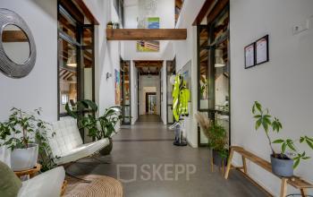 Ruime en lichte entree van een kantoorpand aan Hamersveldseweg 120, Leusden. De entree is voorzien van zitgelegenheid en decoratieve planten.