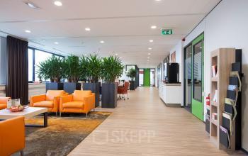 Kantoorruimte huren aan de Europalaan 24, Maastricht-Airport, modern interieur met zitgedeelte, planten en werkplekken.