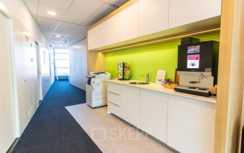 Heldere kitchenette in een kantoorpand op Avenue Ceramique 221, Maastricht, met een koffiezetapparaat en kasten. Ideaal bij het huren van kantoorruimte.