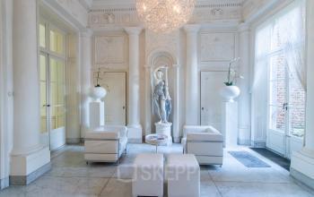 Elegante kantoorruimte met klassieke beeldhouwkunst en moderne witte meubels op Markt 14, Maastricht, ideaal voor wie kantoorruimte wil huren in een historisch kantoorpand.