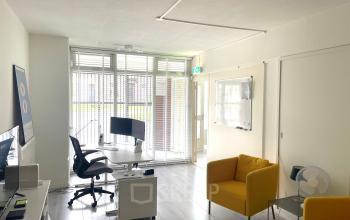 Modern kantoor met glaswand, twee bureaus en een comfortabele stoel op Wilhelminasingel 44-46 in Maastricht. Mogelijkheid tot kantoorruimte huren met een lichte, eigentijdse uitstraling.