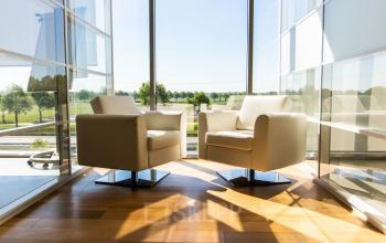 Moderne kantoorruimte in Made met twee comfortabele stoelen naast grote ramen, die uitzicht bieden op een groen landschap. Ideale locatie voor kantoorruimte huren.