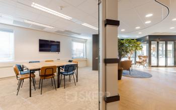 Moderne kantoorruimte in Meppel met grote ramen, glazen scheidingswand en stijlvolle verlichting om het werken comfortabel te maken. Ruimte ingericht met vergadertafel en stoelen. Ideaal voor bedrijven die kantoorruimte willen huren.