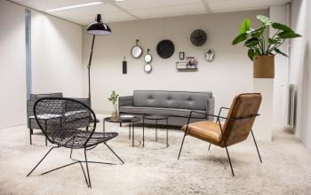 Stijlvol ingerichte lounge in kantoorpand Rijksweg 79, Naarden met moderne meubels en decoratieve elementen aan de muur.