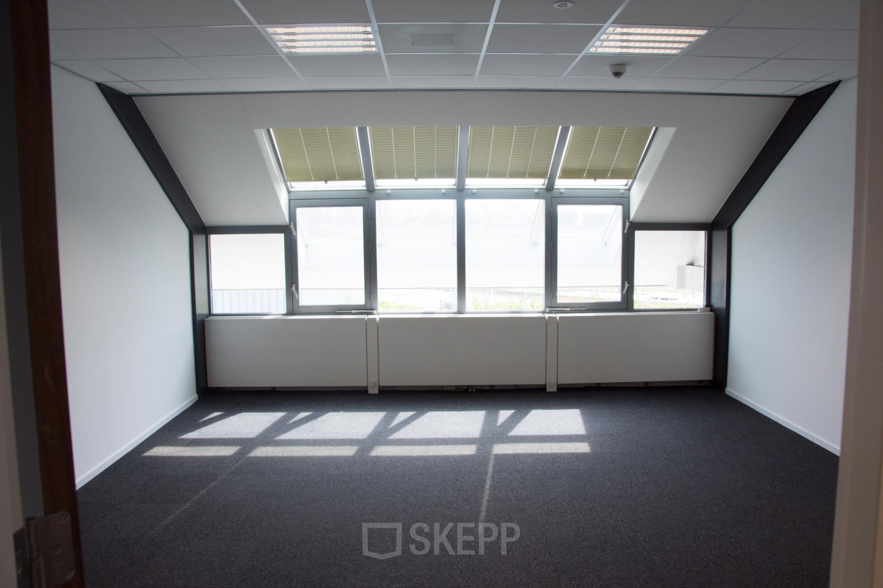 Kantoorruimte huren aan de Rijksweg 79 in Naarden, met groot raam voor natuurlijk licht en uitzicht op de omgeving.
