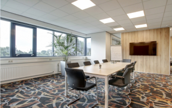 Vergaderruimte in het kantoorpand Nevelgaarde 8-35, Nieuwegein, voorzien van een lange tafel met stoelen en een grote monitor aan de muur. Kantoorruimte huren mogelijk.