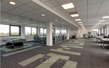 Ruime kantoorruimte in Nieuwegein met grote ramen en een pooltafel. Moderne werkplekken en vergaderruimtes beschikbaar voor huur in een open opstelling.