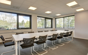 Kantoorruimte Nevelgaarde 8-35 in Nieuwegein met moderne vergadertafel en comfortabele stoelen, grote ramen met natuurlijk licht en uitzicht op groen, ideaal voor zakelijke bijeenkomsten.