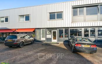 Modern kantoorpand op Nijverheidsweg 9B in Nieuwegein met geparkeerde auto's voor de ingang en een uitnodigende entree.