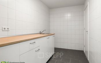 Kantoorruimte te huur met een functionele pantry in kantoorpand aan de Nijverheidsweg 9B, Nieuwegein. De ruimte heeft witte tegels en een houten werkblad met spoelbak.