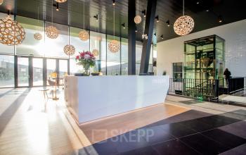 Moderne receptie in een kantoorpand op Jonkerbosplein 52, Nijmegen, met een stijlvol ontwerp en grote ramen voor veel natuurlijk licht.
