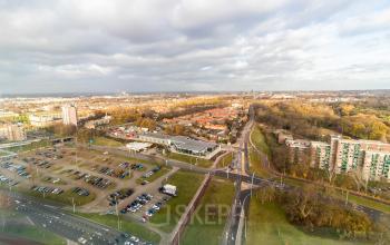 Uitzicht op het kantoorpand en omgeving vanaf Jonkerbosplein 52 in Nijmegen, geschikt voor kantoorruimte huren. Diverse gebouwen en parkeerterreinen omgeven door groen en stedelijk landschap.