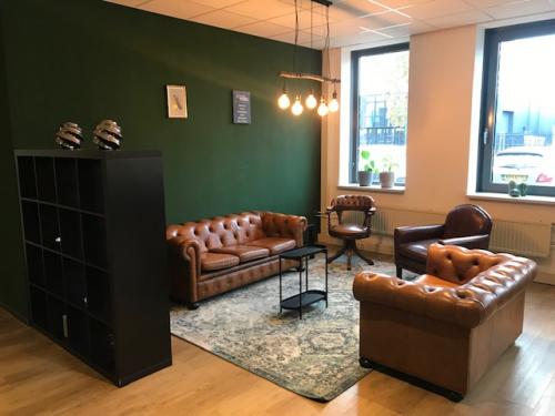 Gezellig ingerichte kantoorruimte met leren banken en vintage tapijt in kantoorpand Kerkenbos 1037, Nijmegen, geschikt voor informele besprekingen.