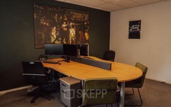 Gemeubileerde kantoorruimte met een grote houten tafel, bureaustoelen en twee beeldschermen, gelegen op Abdis van Thornstraat 74 in Oosterhout Nb.