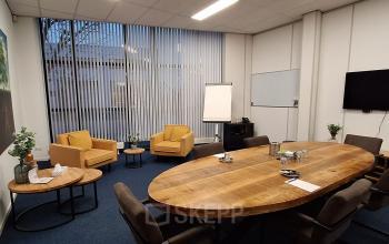 Vergaderruimte in kantoorpand Leeghwaterstraat 25, Reeuwijk, met houten tafel, comfortabele stoelen en audiovisuele apparatuur. Ideale plek voor bedrijfsoverleggen of als kantoorruimte huren.