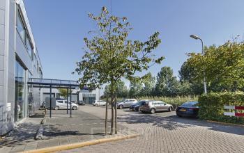 Kantoorpand aan de Leeghwaterstraat 25 in Reeuwijk met parkeergelegenheid voor het gebouw, omringd door groen.