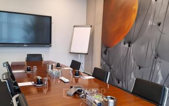 Vergaderruimte met houten tafel, zes stoelen, televisiescherm aan de muur en flip-over in een kantoorpand aan de Leeghwaterstraat 25, Reeuwijk. Geschikt voor kantoorruimte huren.