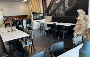 Gemeubileerde kantoorruimte voor verhuur op Leeghwaterstraat 25 in Reeuwijk, met eet- en zitgelegenheden, decoratieve accenten en een stijlvolle wandprint.