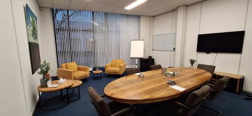 Vergaderruimte in kantoorpand Leeghwaterstraat 25, Reeuwijk, met houten tafel, comfortabele stoelen en audiovisuele apparatuur. Ideale plek voor bedrijfsoverleggen of als kantoorruimte huren.
