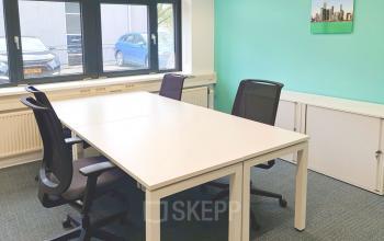 Kantoorruimte huren op Einsteinlaan 28 in Rijswijk met vier bureaustoelen rondom een witte vergadertafel, grote ramen zorgen voor veel lichtinval.