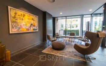 Moderne, stijlvolle kantoorruimte aan Laan van Vredenoord 33 in Rijswijk, met comfortabele stoelen en kunst aan de muur. Ideaal voor wie een kantoorruimte wil huren in een inspirerende omgeving.