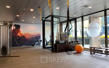 Moderne fitnessruimte in kantoorpand met sportapparatuur en grote ramen bij Laan van Vredenoord 33, Rijswijk. Kantoorruimte huren in deze omgeving biedt ook sportfaciliteiten.