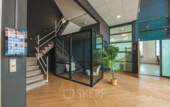 Moderne entree van kantoorpand op Lange Kleiweg 50-62 in Rijswijk met stijlvol interieur, trap, planten en glazen vergaderruimte. Ideaal voor kantoorruimte huren.