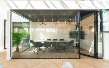 Modern kantoorpand Lange Kleiweg 50-62 in Rijswijk met glazen vergaderruimte, stijlvol ingericht en voorzien van comfortabele stoelen en unieke verlichting. Ideale plek om kantoorruimte te huren voor professionele bijeenkomsten.