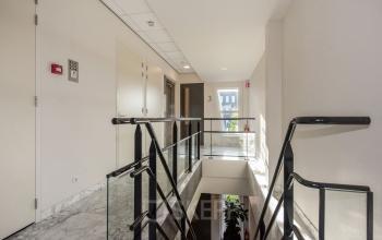 Binnenkant van het kantoorpand op Laan van Vredenoord 17-19, Rijswijk, met een trap en glazen balustrade. Geschikt voor kantoorruimte huren.