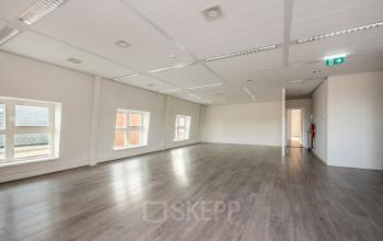 Lichte, ongemeubileerde kantoorruimte met houten vloer en grote ramen aan de Laan van Vredenoord 17-19 in Rijswijk, ideaal voor kantoorruimte huren.