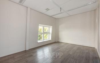 Lege kantoorruimte op Laan van Vredenoord 17-19 in Rijswijk met een raam en lichte houten vloer, ideaal voor kantoorruimte huren.