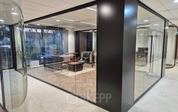 Moderne kantoorruimte op JC van Markenlaan 3 in Rijswijk met glazen wanden, ingerichte zithoek en zicht op vergaderruimte. Geschikt voor degenen die kantoorruimte willen huren.