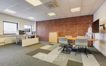 Kantoorruimte huren in Rijswijk, gelegen op Patrijsweg 4-140, met moderne werkplekken, een vergadertafel, en een bakstenen muur als accent.