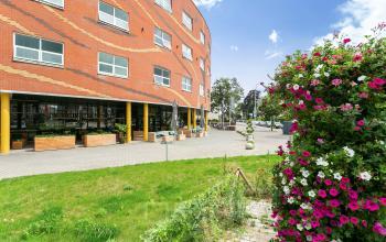 Buitenaanzicht van het kantoorpand aan Kapellerpoort 1 in Roermond, met modern baksteenontwerp en groene omgeving.
