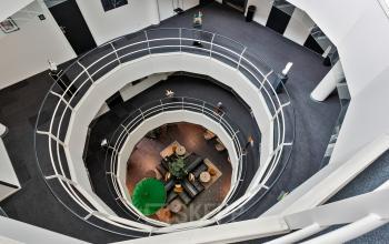 Kantoorpand aan de Kapellerpoort 1 in Roermond. Binnenkant met moderne inrichting en een opvallend atrium met meerdere verdiepingen zichtbaar.