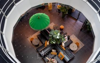 Kantoorruimte huren in Roermond, gelegen op Kapellerpoort 1, met een open lounge met zitbanken, tafels en groene accenten.