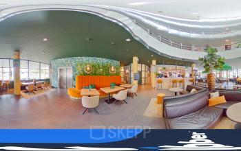 Gezellige entree van kantoorpand bij Kapellerpoort 1, Roermond. Moderne inrichting met zitgroepen, veel natuurlijk licht en een groene wand.