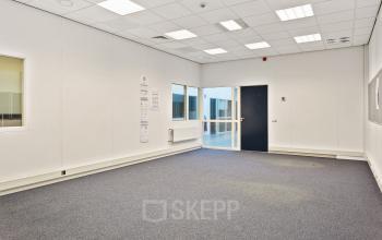 Leeg kantoor in Roermond op Noordhoven 2. Het kantoorpand heeft blauwe vloerbedekking en witte muren, met grote ramen voor natuurlijk licht. Ideale ruimte voor kantoorruimte huren met flexibele mogelijkheden.