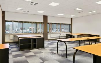 Lichte kantoorruimte met meerdere bureaus en grote ramen in Roermond, ideaal om te huren voor vergaderingen of als werkruimte.