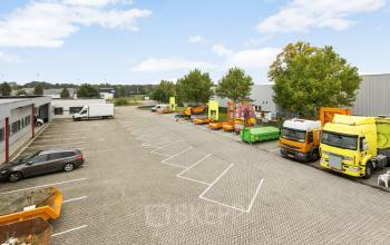 Parkeerterrein bij kantoorpand op Noordhoven 2 in Roermond, met diverse voertuigen en vrachtwagens geparkeerd. De ruimte biedt mogelijkheden voor kantoorruimte huren in een goed bereikbare omgeving.