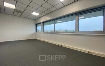Lege kantoorruimte met grote ramen in het kantoorpand op Noordhoven 19, Roermond. Heldere verlichting en uitzicht op de omgeving maken het geschikt voor diverse kantooractiviteiten.