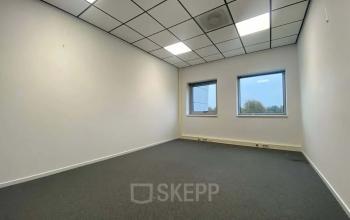 Kantoorruimte huren op Noordhoven 19, Roermond: lichte, ongefurniseerde ruimte met ramen en grijze vloerbedekking, ideaal voor zakelijke activiteiten.