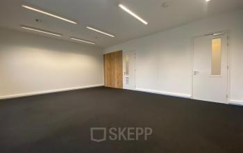 Leeg kantoorpand op Boven de Wolfskuil 3 in Roermond met witte muren en donkere vloerbedekking, perfect voor kantoorruimte huren.