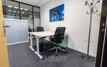 Kantoorruimte met bureau en stoelen bij Rotterdam Airportplein 22. De kamer is voorzien van kantoormeubilair en een grote kast, ideaal voor werk en vergaderingen.