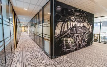 Moderne kantoorruimte huren bij Rotterdam Airport met gang voorzien van glazen wanden en uniek luchtvaartontwerp.