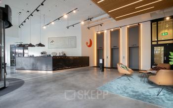Moderne kantoorruimte bij Prins Alexanderplein 5 in Rotterdam met een stijlvolle receptiebalie, strategisch geplaatste verlichting en comfortabele zitgedeeltes voor korte vergaderingen. Ideaal om een kantoor te huren in een dynamische omgeving.