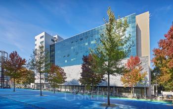 Modern kantoorpand aan het Prins Alexanderplein 5, Rotterdam Alexander. Glasgevel met bomenrij en blauwe bestrating op de voorgrond.