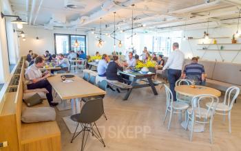 Kantoorpand aan Marten Meesweg 8-10 in Rotterdam Alexander, met diverse medewerkers aan tafels bezig met zakelijke activiteiten in een moderne gemeubileerde werkruimte.