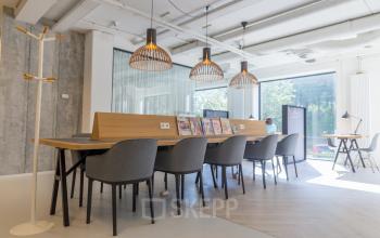 Kantoorruimte huren op Marten Meesweg 8-10 in Rotterdam Alexander, voorzien van moderne open werkplekken met ruime tafel, tijdschriften en comfortabele stoelen.